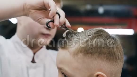 理发师在短发上做发型可爱的男孩坐在椅子上理发视频的预览图