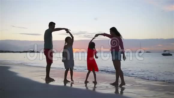 父母和两个孩子在日落时在海滩上玩得很开心四口之家相爱幸福美好视频的预览图