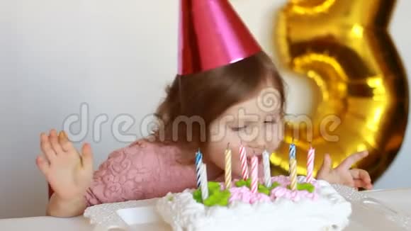 一个快乐的孩子咬一个大蛋糕在桌子上的光背景一个有趣的小女孩吃一个美味的甜点视频的预览图