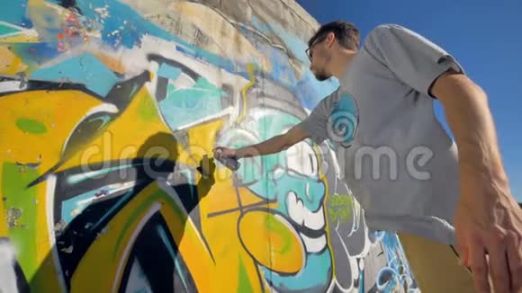 涂鸦艺术家正在墙上画一个黄色的字母从左边看从下面看视频的预览图