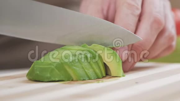 一个男人正在用一把菜刀在切割板上切熟的鳄梨视频的预览图