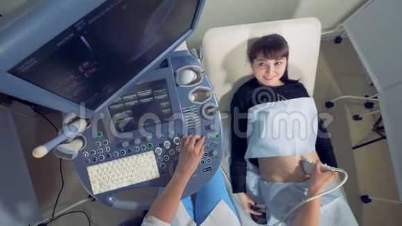 微笑的孕妇观察自己的超声波检查过程视频的预览图