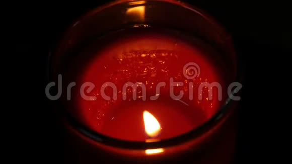 巨大的圆形红色纪念蜡烛在黑暗中燃烧黑色背景上的蜡烛火焰视频的预览图
