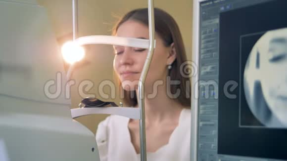 一位年轻女子把头放在一台光学机器上做眼科检查视频的预览图