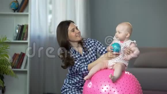 可爱的婴儿跳着球笑着宝贝和慈爱的母亲玩得很开心视频的预览图