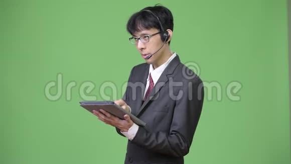 年轻的亚洲商人使用数码平板电脑同时也是呼叫中心的代表视频的预览图