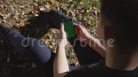 男子手持黑色智能手机绿色屏幕上的城市街道背景在晴天大屏幕科布尔街视频的预览图