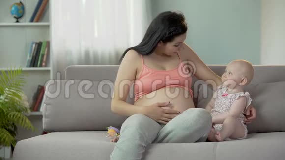 女人喜欢怀孕抚摸她的大肚子拥抱可爱的女婴视频的预览图