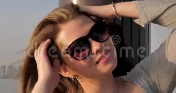 戴眼镜的年轻白种人女孩站在夕阳的柱子上视频的预览图