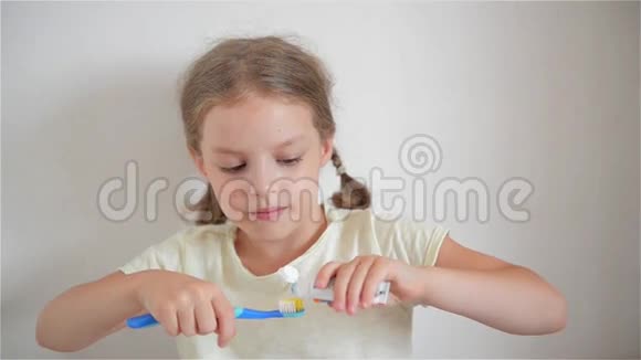 浴室里的小女孩把牙膏涂在牙刷上视频的预览图