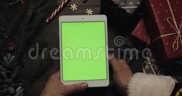 圣诞老人手里拿着绿色屏幕的白色平板电脑铬钥匙上景垂直位置圣诞节视频的预览图