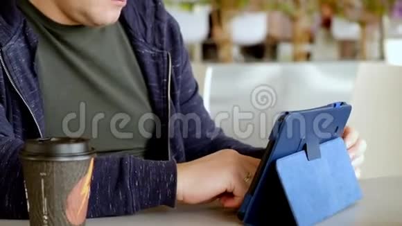 一位中年男子在食品法庭上使用平板电脑和喝咖啡视频的预览图