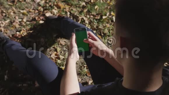 男子手持黑色智能手机绿色屏幕上的城市街道背景在晴天大屏幕科布尔街视频的预览图