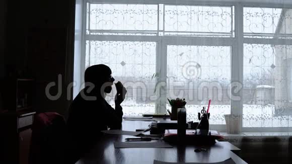一个女人在窗户背景上吃汉堡包的剪影视频的预览图