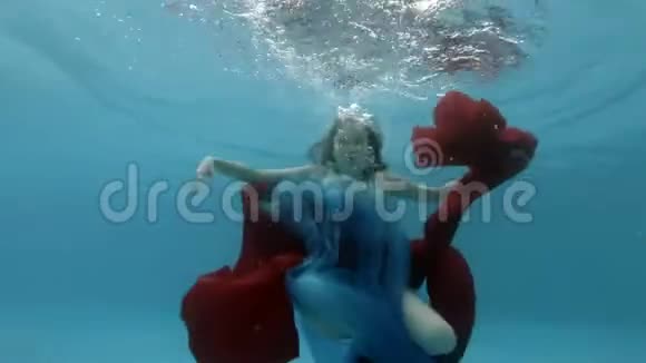 一个穿着连衣裙的漂亮少女在游泳池里游泳在水面附近玩红蓝相间的布视频的预览图