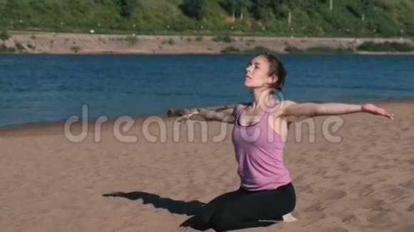 在城市河边的海滩上伸展瑜伽的女人美丽的城市景色呼吸练习视频的预览图