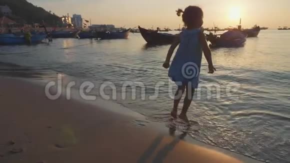 可爱的小女孩穿着一件连衣裙在海滩上溅起水花视频的预览图