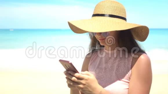 暑假在海滩上使用手机应用程序的旅行妇女视频的预览图