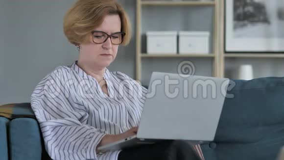 失落沮丧的老年妇女在笔记本电脑上工作视频的预览图