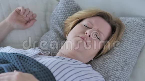 睡在床上的头戴头巾的老年妇女视频的预览图