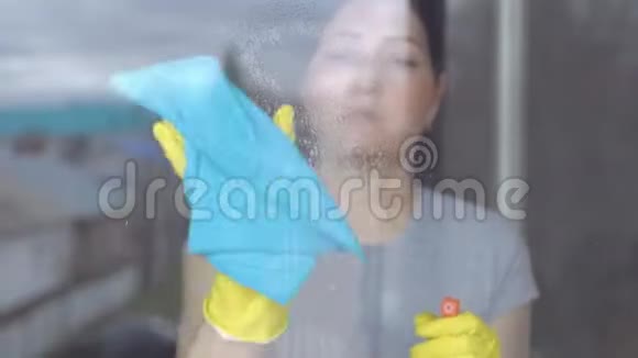 戴着黄色手套的女人用蓝色抹布擦窗户视频的预览图