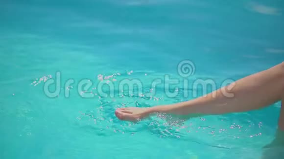 无法辨认的女孩坐在池边在炎热的晴天用脚泼水夏天玩的年轻女人视频的预览图