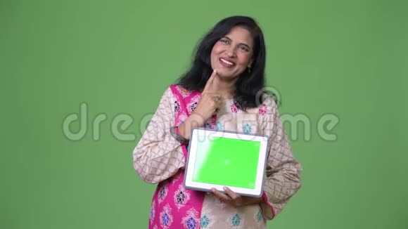 成熟快乐美丽的印度女人一边思考一边展示数字平板电脑视频的预览图
