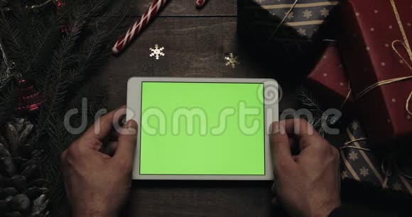 男性手拿着绿色屏幕的白色平板电脑铬钥匙上景垂直位置圣诞新年视频的预览图