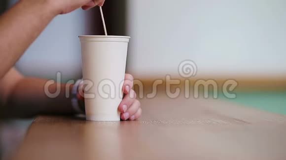 男性手的特写镜头在咖啡馆里用咖啡搅拌杯子里的糖视频的预览图