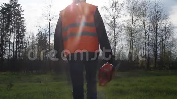 一个带着电锯和信号背心的人走进森林视频的预览图