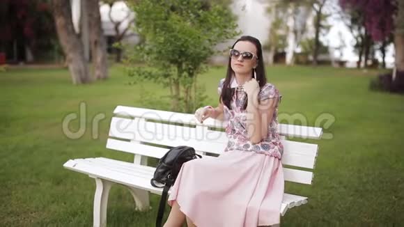 年轻漂亮的女人在城市公园的长椅上放松视频的预览图