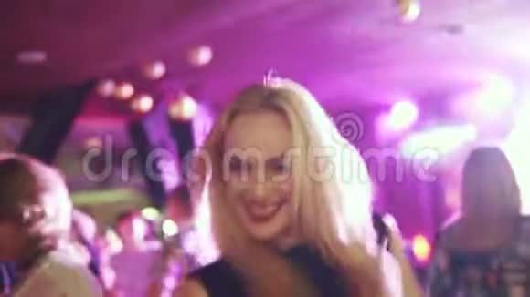 年轻迷人的女人在一场音乐会上在五颜六色的灯光下跳舞视频的预览图
