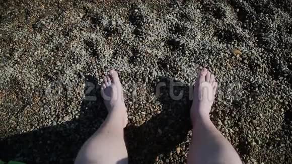 夏季概念女性在鹅卵石海滩上的双腿而女性则在皮肤上涂防晒霜视频的预览图
