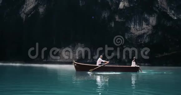 浪漫的情侣在湖中央有一艘木船男人在划船他的女朋友在划船视频的预览图