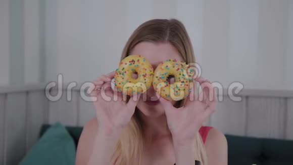 漂亮的女孩摆姿势手里拿着甜甜圈在咖啡馆的桌子上视频的预览图
