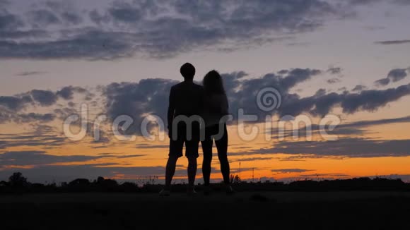 剪影浪漫的情侣看着绯红的夕阳相拥而归视频的预览图