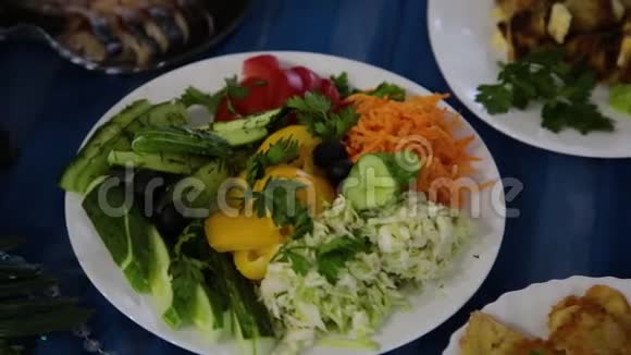 在桌子上的盘子里放着草药的沙拉和不同的肉菜视频的预览图