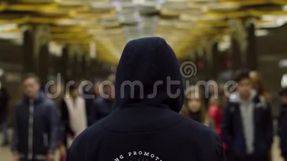 后视一男子身穿深蓝色连帽衫就站在车站的一群人面前反抗的概念关门视频的预览图
