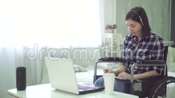 残疾青年妇女肖像轮椅家庭远程工作电脑耳机视频的预览图