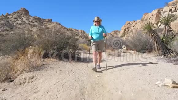 帽子里的女人走在沙漠中的小径上仙人掌周围视频的预览图