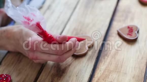 心形饼干装饰工艺与粉红色奶油特写女性手握一管粉红色奶油视频的预览图