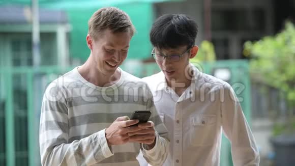 两个快乐的多民族商人在户外的街道上一起用电话微笑视频的预览图