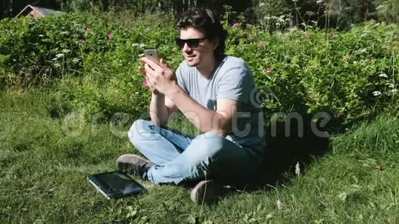 在阳光明媚的日子里坐在公园里的人正在用手机打字自由职业视频的预览图