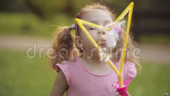 自信活泼可爱的小女孩吹巨大的空气肥皂泡吹风机中型特写视频的预览图