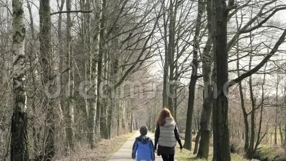 妈妈带着儿子散步有孩子的女人走过农村美丽的小路通向小巷视频的预览图