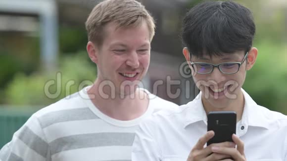 两个快乐的多民族商人在户外的街道上一起使用电话视频的预览图