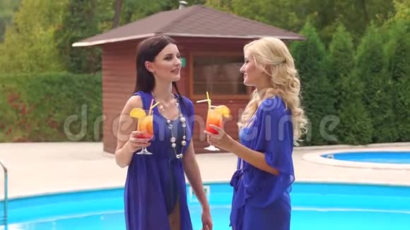 两个带着鸡尾酒的女人在泳池边放松视频的预览图