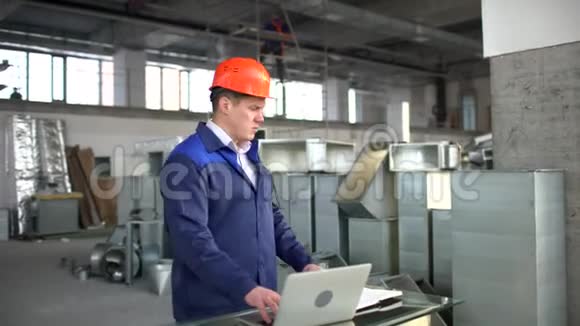 戴着安全帽的工厂工人正在使用带有工程软件的笔记本电脑空调和空调风管视频的预览图