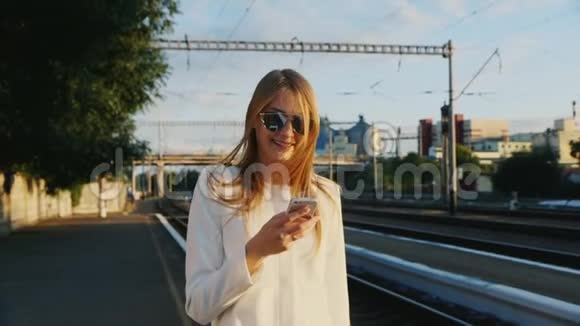 一位商务女性正在沿着火车站步行使用智能手机旅行概念中的沟通视频的预览图