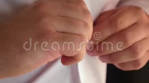 男人在衬衫上扣一个扣子特写镜头商人穿上白色衬衫上班族早上穿衣服男人视频的预览图